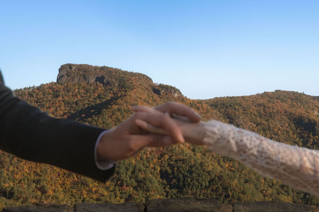 Couple holding hands with Blue Ridge mountain fall foliage in the background during NC mountain elopement